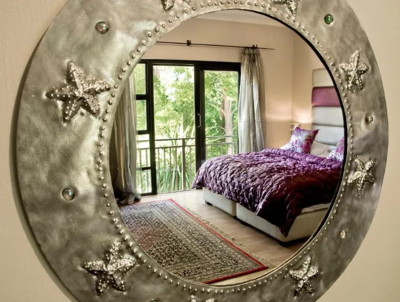 Southern Light bedroom reflected in a decorative round mirror