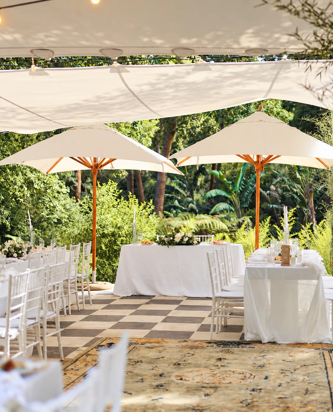 Garden terrace set for a celebration with white tables and parasols